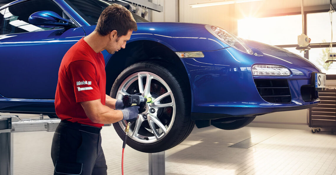 Technician servicing a tire on a blue Porsche