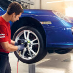 Technician servicing a tire on a blue Porsche